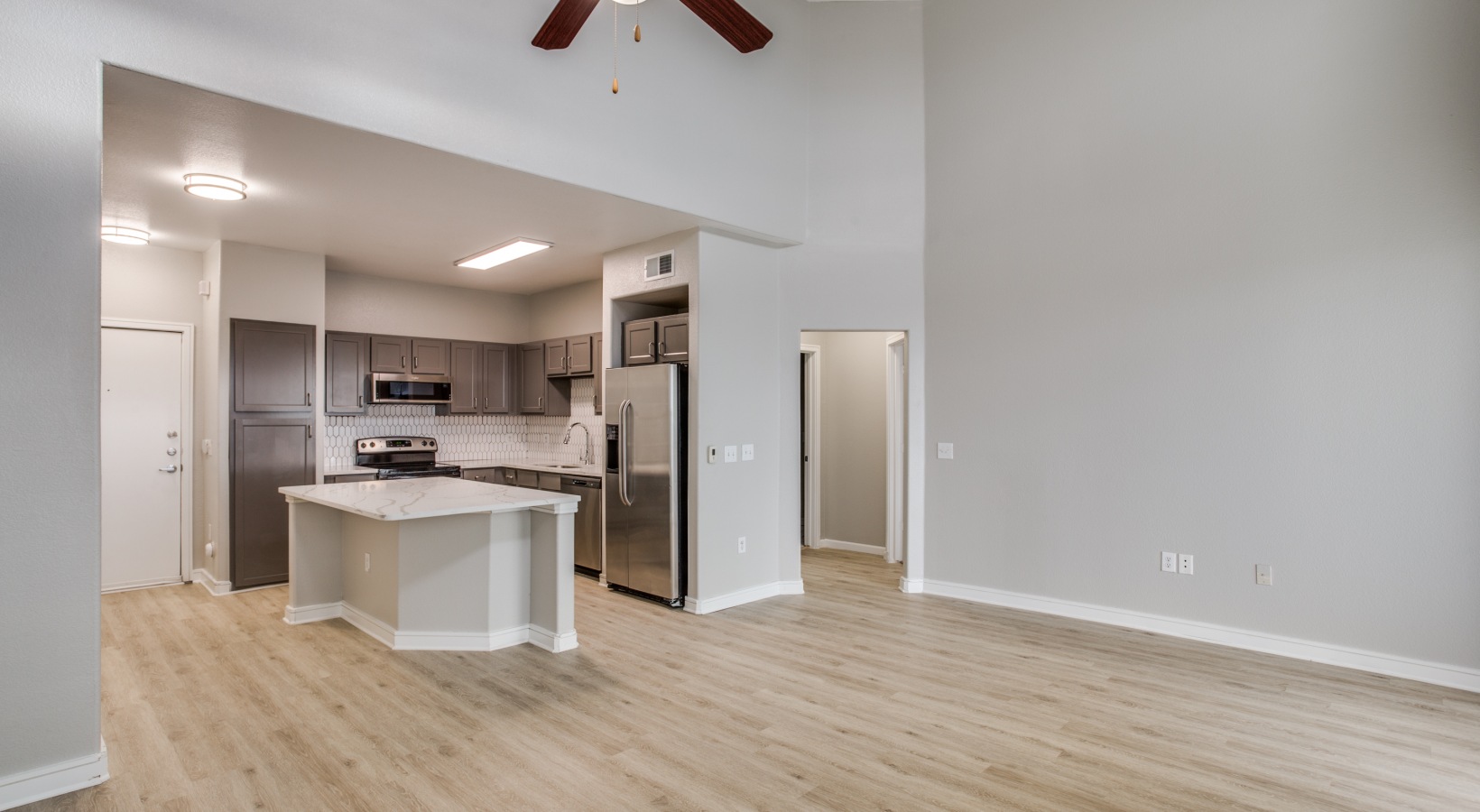 an empty kitchen with hardwood floors and ceiling fans at The  Franklin at Samuels Ave