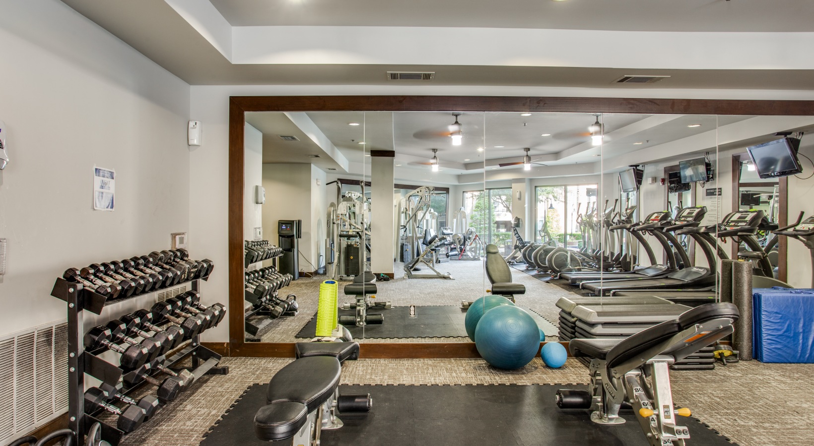 a gym room with exercise equipment and mirrors at The  Franklin at Samuels Ave