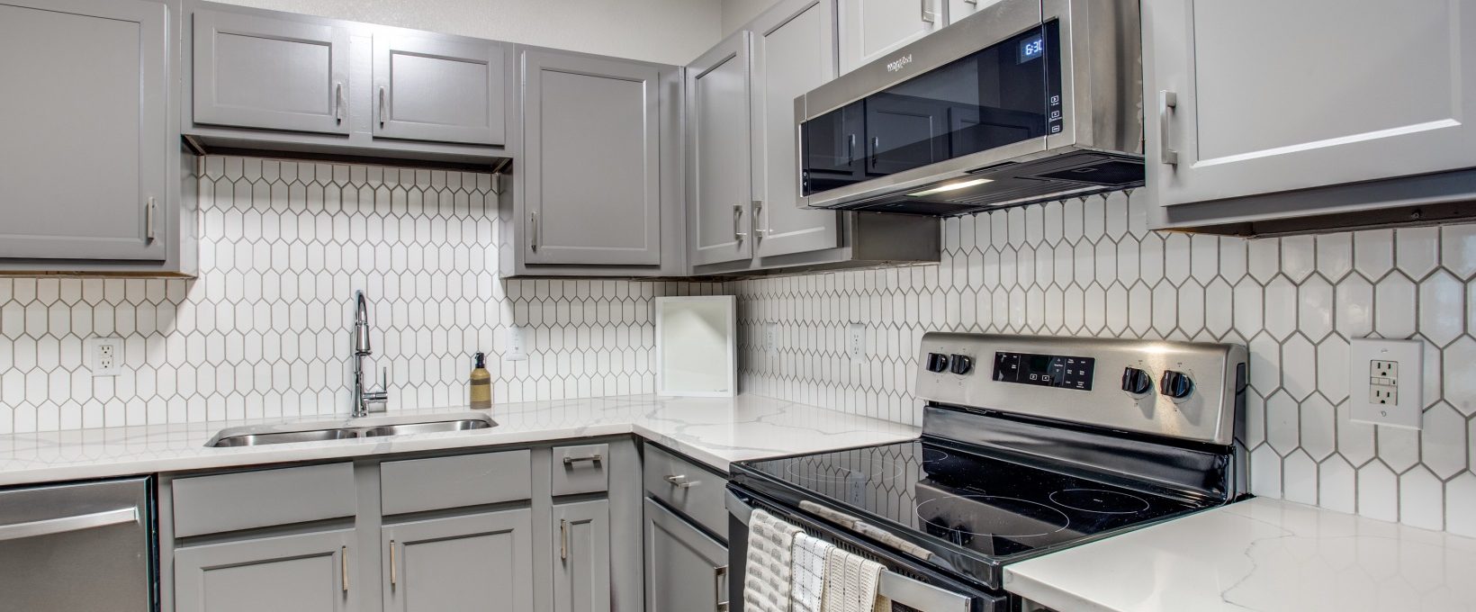 a kitchen with stainless steel appliances and white cabinets at The  Franklin at Samuels Ave