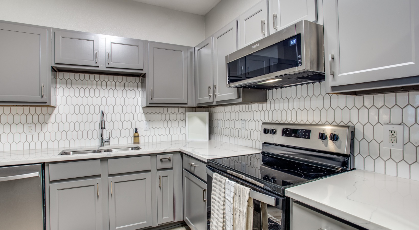 a kitchen with stainless steel appliances and white cabinets at The  Franklin at Samuels Ave