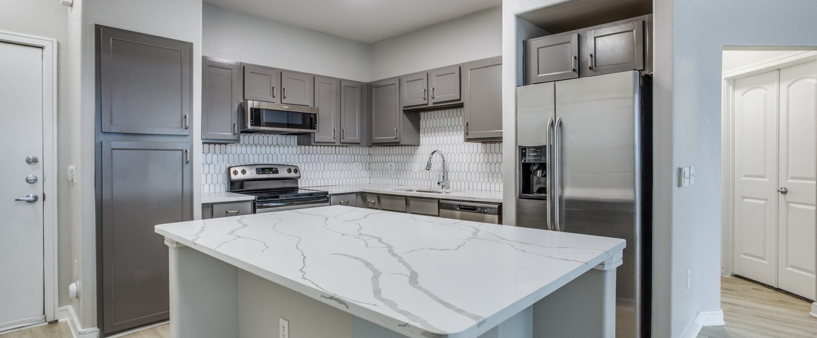 a kitchen with stainless steel appliances and granite counter tops at The  Franklin at Samuels Ave