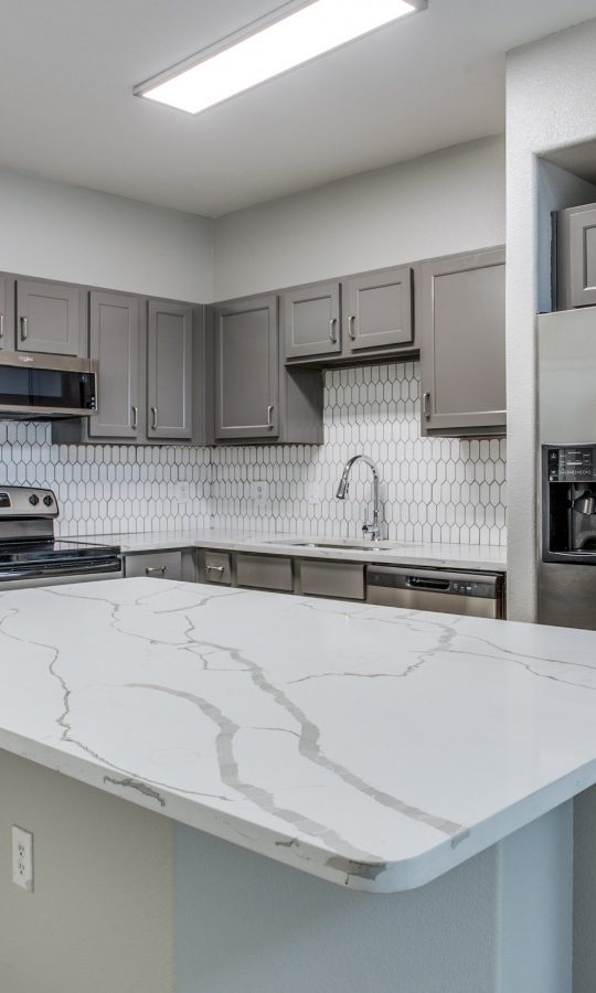 a kitchen with stainless steel appliances and granite counter tops at The  Franklin at Samuels Ave