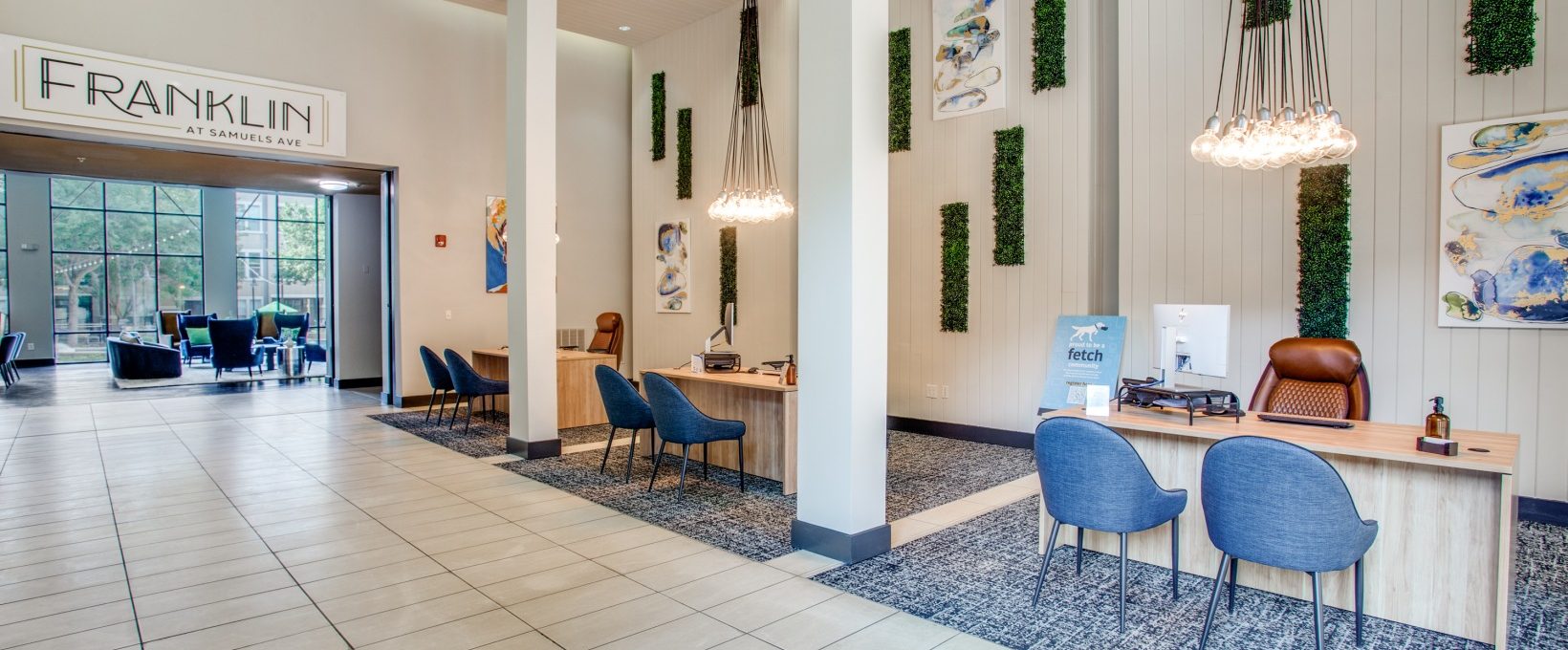 the lobby of a hotel with blue chairs and a large sign at The Franklin at Samuels Ave