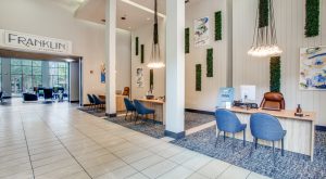 the lobby of a hotel with blue chairs and a large sign at The  Franklin at Samuels Ave