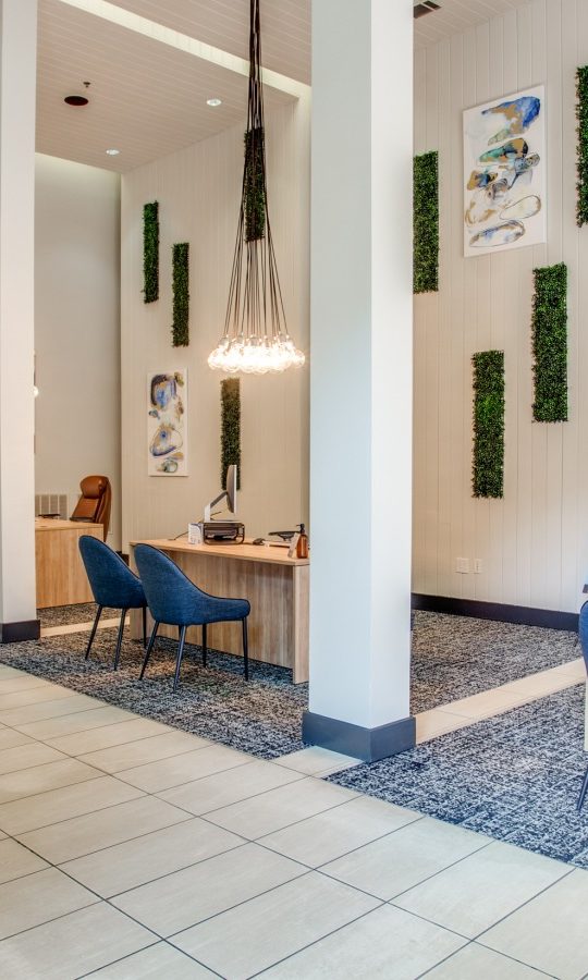 the lobby of a hotel with blue chairs and a large sign at The Franklin at Samuels Ave