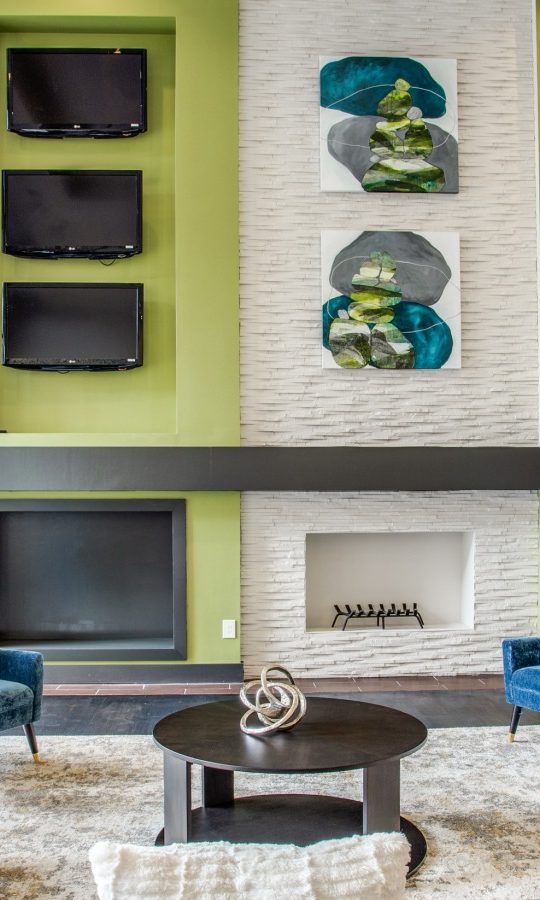 a living room with blue and green accents and a fireplace at The  Franklin at Samuels Ave